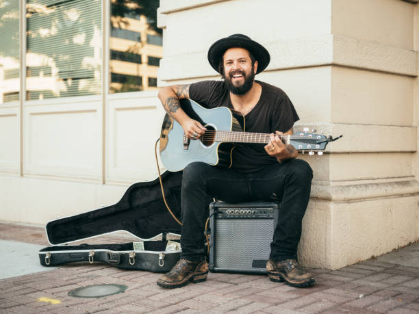 Busking Street Musician A busker street musician playing music for tips on a city sidewalk. solo performance stock pictures, royalty-free photos & images