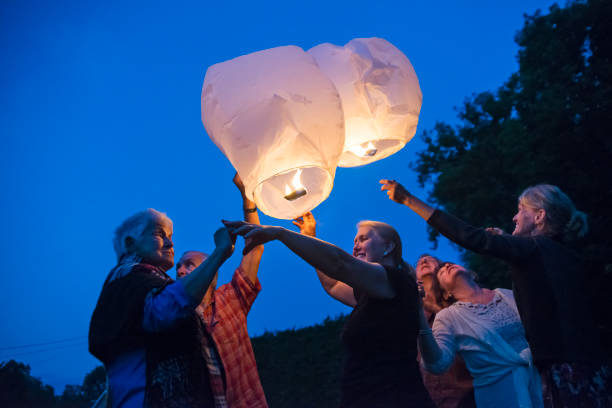 istock Group of seniors lighting flying chinese lanterns at dusk. 1007442314