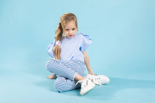 istock A girl in blue clothes is sitting on a blue background. 1007444436