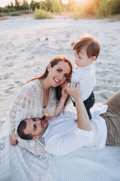 istock smiling parents spending time with adorable son on beach with sunlight 1007444682