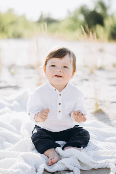 istock adorable boy sitting on white blanket on sand 1007444684
