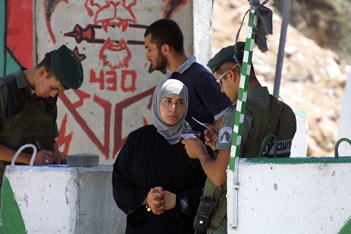 Jerusalem, Israel - Aug. 9, 2002:  An Israeli Border Policeman checks a young Palestinian woman's documents as she enters the city from the West Bank.