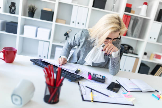 istock Young girl with glasses works in the office with documents, calculator and computer. 1007445392