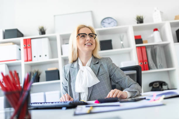 istock Young girl with glasses works in the office with documents, calculator and computer. 1007445396