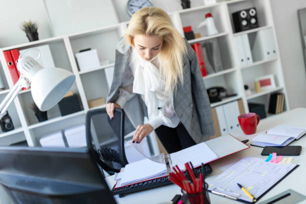 istock A young girl stands near a table in the office and scrolls through a folder with documents. 1007445420