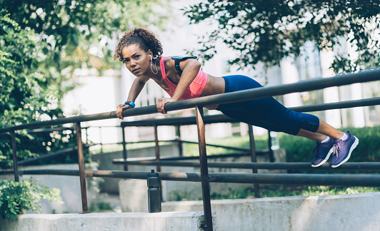 Young fit woman doing push-ups exercises leaning on the fence
