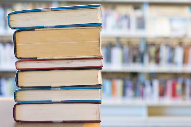 istock Stack of hardcover books against blurry library shelf background 1007461322