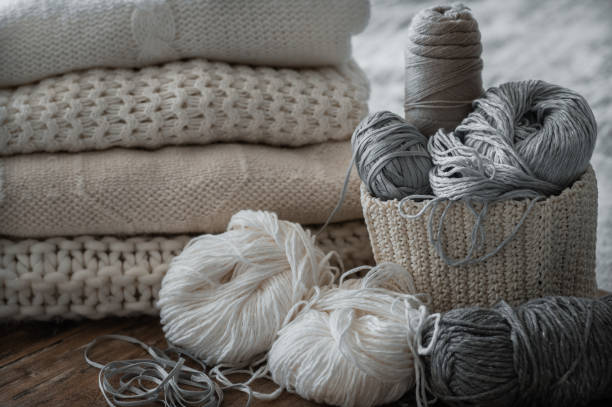 istock A woven basket with white and gray thread for knitting and knitting needles. White sweaters and yarn for knitting closeup. Winter 1007461908