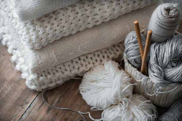 istock A woven basket with white and gray thread for knitting and knitting needles. White sweaters and yarn for knitting closeup. Winter 1007461986