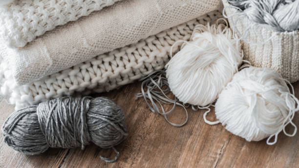 istock A woven basket with white thread for knitting and knitting needles. White sweaters and yarn for knitting closeup. Place for text 1007462006