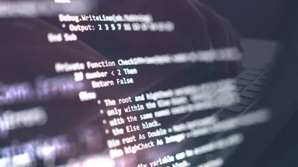 Computer language script and coding on screen with a man reflection in the background