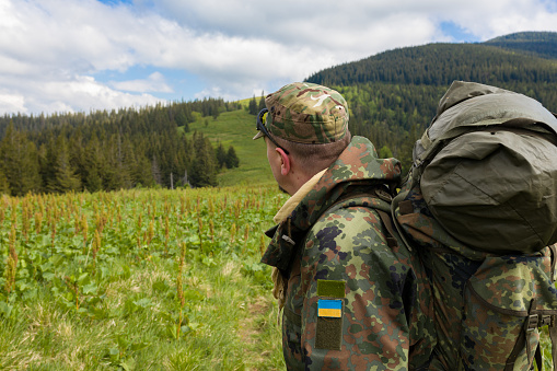 Soldier with a backpack in the mountains enjoying the rural view
