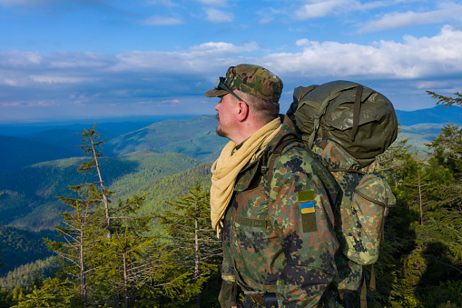 Army man enjoying the view on mountain top in spring in Carpathian mountains