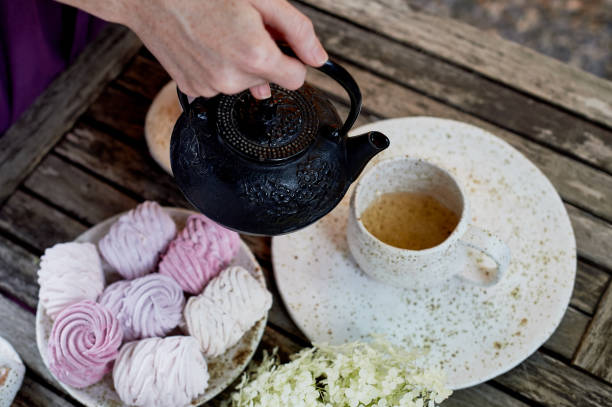 istock Women's hands, pouring tea into a Cup, the table is set in the air. Marshmallow.Hydrangea 1007479910