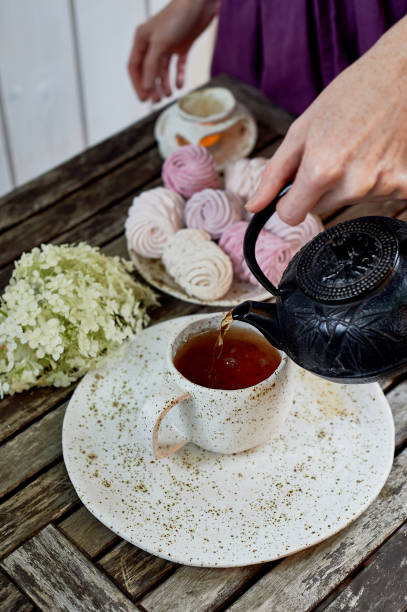 istock Women's hands, pouring tea into a Cup, the table is set in the air. Marshmallow.Hydrangea 1007479984