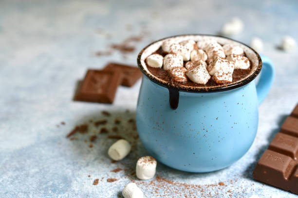 Homemade hot chocolate with mini marshmallow Homemade hot chocolate with mini marshmallow in a blue enamel mug on a light slate background.Rustic style. hot chocolate stock pictures, royalty-free photos & images