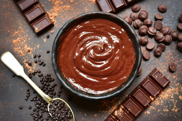 Chocolate ganache in a black bowl with ingredients for making stock photo