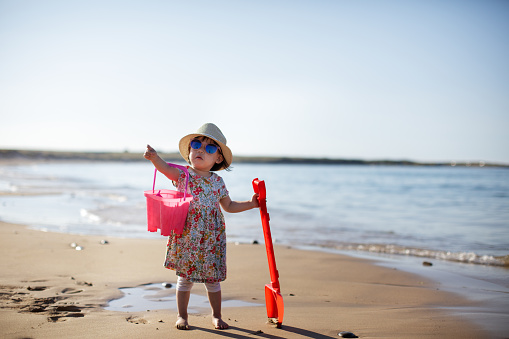 baby girl wearing sunglasses playing on the summer beach