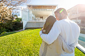Young Couple standing in front of a modern new house.