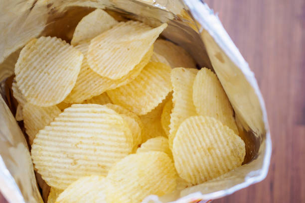 istock Potato chips in open snack bag close up on table floor 1007525050