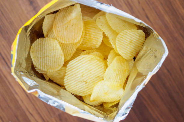 istock Potato chips in open snack bag close up on table floor 1007525052