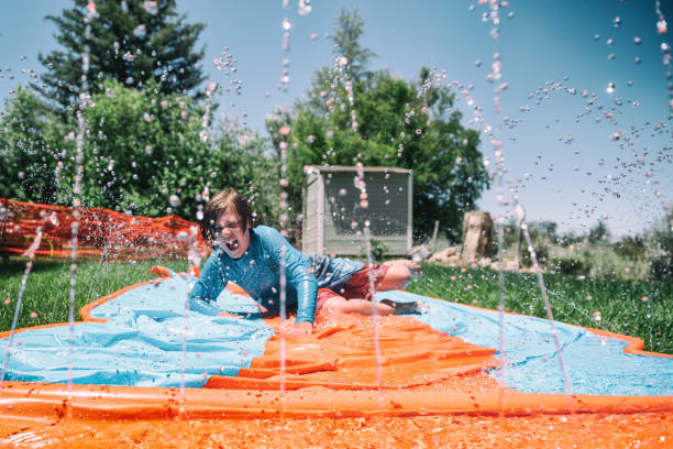 istock Child stays cool in a heat wave by playing on slip and slide 1007525236