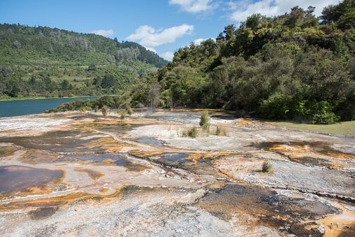 Stunning orange microbial mats with mineral deposits and Lake Ohakuri view at the lush geothermal reserve, Orakei Korako, in Rotorua, New Zealand