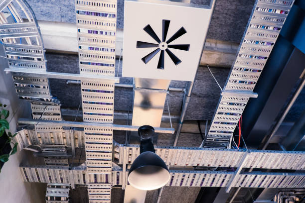 Industrial style office ceiling with metal ventilation ducting, electrical and computer cables, lighting, and pipes in Auckland, New Zealand, NZ