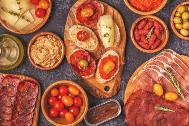 istock Typical spanish tapas concept. Concept include slices jamon, chorizo, sausage, bowls with olives, tomatoes, anchovies,  mashed chickpeas, cheese. 1007624892