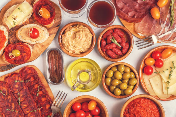 istock Typical spanish tapas concept. Concept include slices jamon, chorizo, sausage, bowls with olives, tomatoes, anchovies,  mashed chickpeas, cheese. 1007624902
