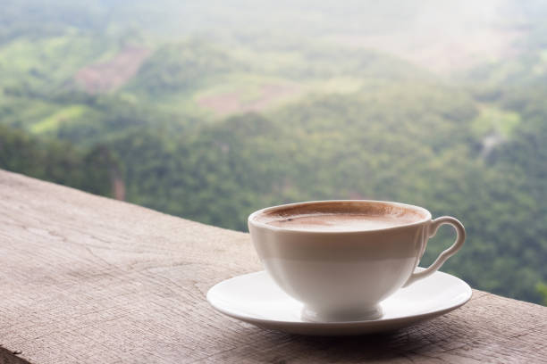 A cup of coffee on the table and a beautiful mountain background. A cup of coffee on the table and a beautiful mountain background. decaffeinated stock pictures, royalty-free photos & images