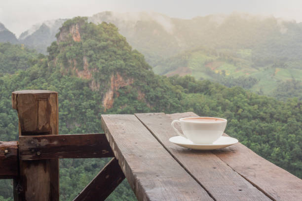 A cup of coffee on the table and a beautiful mountain background.