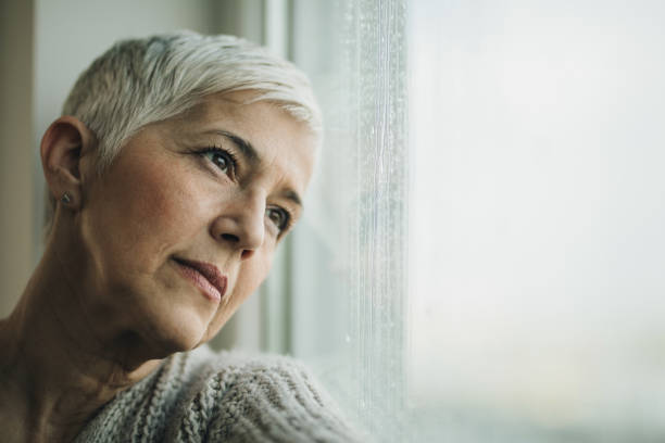 istock Pensive mature woman day dreaming by the window. 1007633148