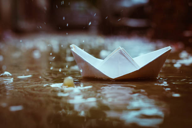istock Paper boat floating in water puddle created by monsoon rains 1007640328