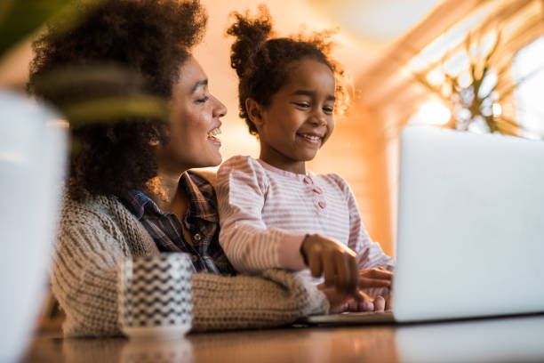istock Happy black mother and daughter using laptop at home. 1007642890