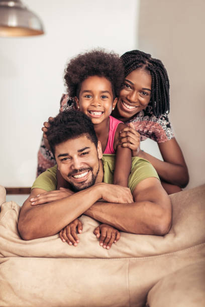 glückliche familie posiert auf der couch zusammen zu hause im wohnzimmer - joy of living stock-fotos und bilder
