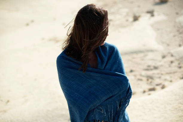 istock Brunette woman in blue cloth standing in desolate windy landscape. Rear view. 1007664896