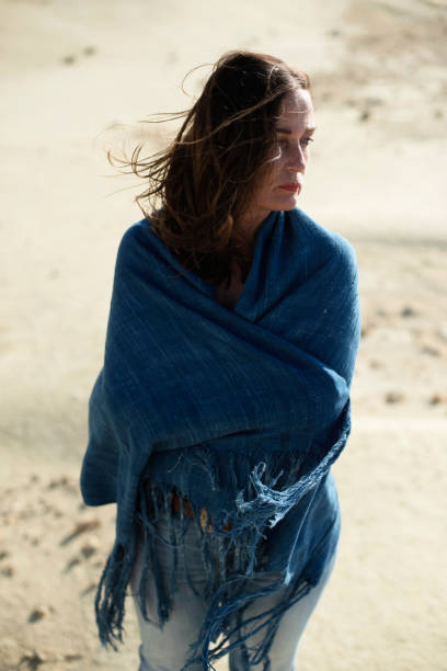 istock Brunette woman in blue cloth standing in desolate windy landscape. 1007664902