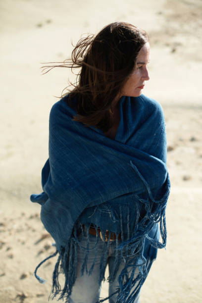 istock Brunette woman in blue cloth standing in desolate windy landscape. 1007664936