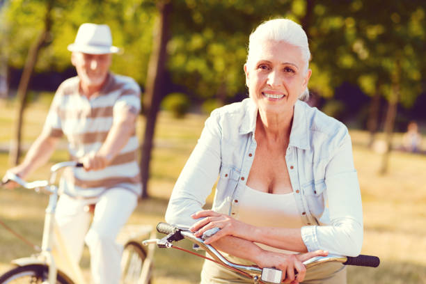 istock Positive minded elderly lady smiling while leaning on bicycle 1007665244