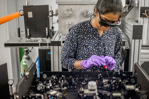 Young Female Researcher Maintaining High Frequency Laser Used for New Materials Research.