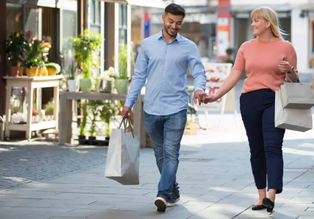 shopping: laughing couple with shopping bags walks through streets