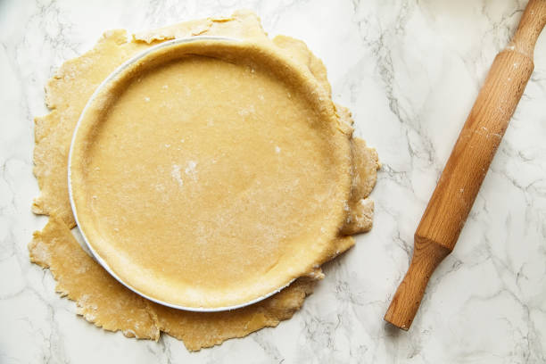 rouler une pâtisserie pour cuire une tarte et il piquant avec une fourchette. concept de recette - tarte sucrée photos et images de collection