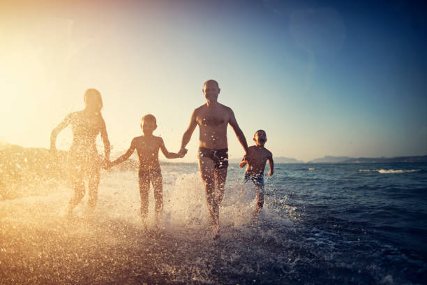 istock Father and kids running on the beach 1007688862