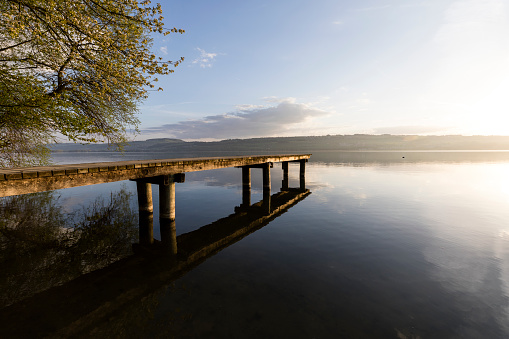 Wonderful morning mood on Lake Sempach in Switzerland. A wooden walkway leads out onto the lake.