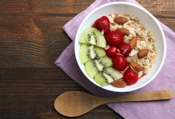 Ingredients for a healthy breakfast; Oatmeal, strawberry, kiwi and nuts on a wooden background