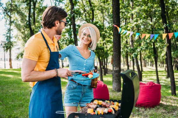 istock cheerful couple having barbecue in summer park 1007699146