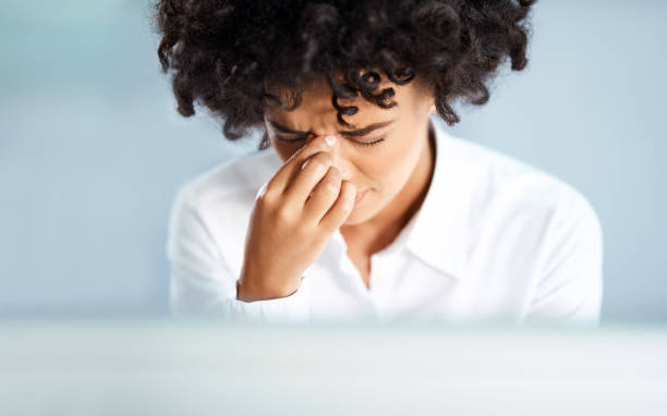 Her workday has started to tense up Shot of a young businesswoman looking stressed out while working in an office sinusitis photos stock pictures, royalty-free photos & images