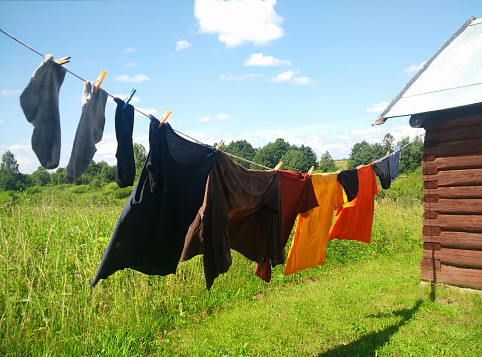 Clothes hanging on washing line against a blue sky and green field. Washing line with drying clothes in courtyard.