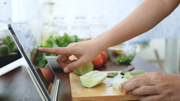 Asian woman use finger slide on tablet screen prepare ingredients for cooking follow cooking online video clip on website. cooking content on internet technology for modern lifestyle concept introducir dedo mujer asiática uso tablet pantalla preparar ingredientes para cocinar el siguiente clip de vídeo en línea en el sitio web de cocina. contenido en la tecnología de internet para el concepto de estilo de vida moderno de cocina